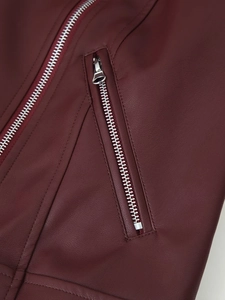 Gros plan d'une veste en cuir bordeaux avec fermeture éclair argentée et coutures