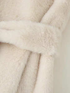 Macro view showing the soft texture and plush fibers of the faux fur coat in beige