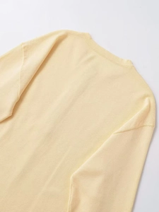 Detail shot of cream knit sweater showing ribbed crew neck texture and soft fabric
