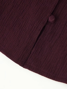 Detail view of burgundy pleated fabric with matching fabric-covered button and seams