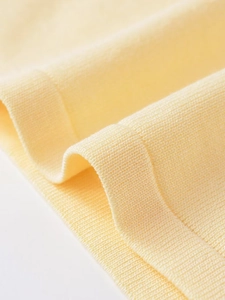 Macro detail of the soft yellow fine knit fabric texture and ribbed cuff edge finish