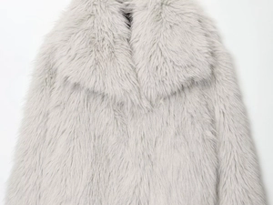 Gros plan d'un manteau en fausse fourrure gris clair avec grand revers et peluche