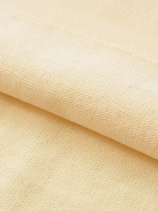 Detailed macro texture of cream knitted fabric with clear breathable stitching patterns
