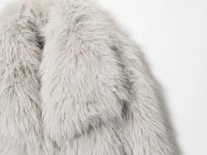 Détail d'un manteau en fausse fourrure gris clair montrant la texture douce du revers