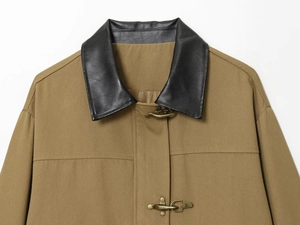 Detail of khaki utility jacket featuring black leather collar and brass metal latch fasteners