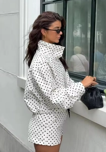 Outdoor-Aufnahme einer schicken schwarz-weißen Polka-Dot-Jacke mit Stehkragen und Reißverschluss