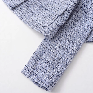 Close-up of blue tweed jacket fabric showing intricate woven texture and sleeve detail
