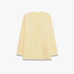 Women's pale yellow long sleeve henley shirt with a relaxed fit and buttoned neckline