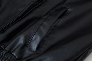 Détail d'une veste en similicuir noir avec poche latérale et coutures élastiques