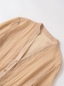 Detailed close-up of pleated champagne chiffon fabric with vintage brown buttons