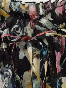 Detalle de blusa de gasa floral con volantes en hombros y ribete de encaje negro