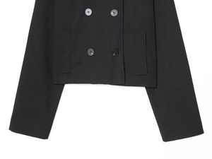 Detail view of double-breasted closure and side pockets on black short wool coat