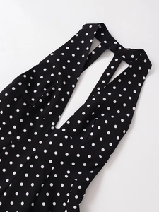 Detail of V-neck halter dress featuring black and white polka dot print and cross back straps