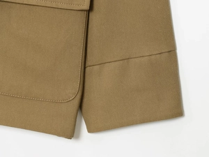 Macro view of khaki twill fabric showing detailed stitching on cuffs and pocket flaps