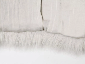 Détail rapproché du tissu satiné lisse et de la garniture en fausse fourrure sur un manteau