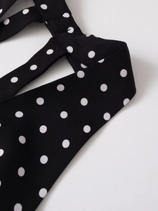 Detail shot of V-neck halter dress featuring classic black and white polka dot fabric