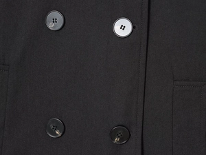 Detailed macro view of four marble-textured resin buttons on black wool blend fabric