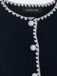 Detailed macro shot of the navy knit cardigan with grey scallop embroidery and fabric buttons