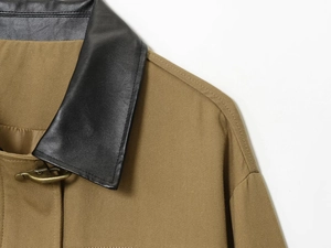 Detail of khaki twill jacket featuring black leather collar and bronze metal hook closure