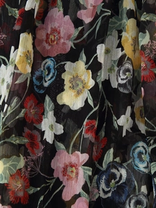 Gros plan d'un imprimé floral vibrant sur tissu noir léger avec une texture plissée délicate