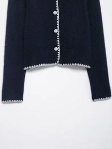 Close-up of navy knit cardigan featuring white scalloped edges and textured soft fabric