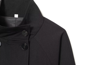 Detail of wool coat with stand collar, smooth woven fabric, and large glossy black buttons
