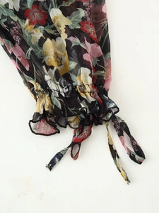 Detalle de los puños de vestido en gasa floral con volantes elásticos y lazos decorativos