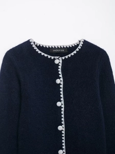 Detailed texture of dark blue wool knit cardigan with grey scalloped edge and buttons