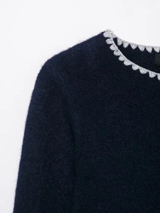 Detail of dark blue knit sweater with contrasting grey scalloped lace collar