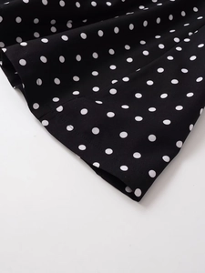 Detail of V-neck dress showing black and white polka dot fabric and neat stitching
