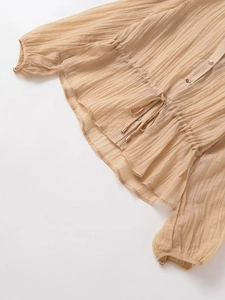 Detail showing the pleated fabric texture and drawstring waist of the light brown blouse