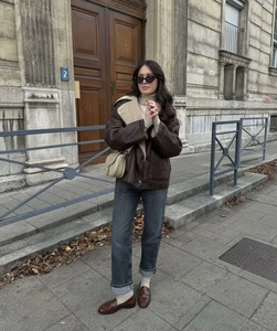 Detail of dark brown faux shearling jacket with cream wool collar in a street style look