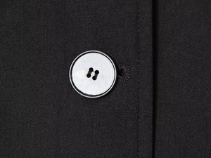 Macro shot of silver-tone buttons and fine fabric texture on the black wool coat