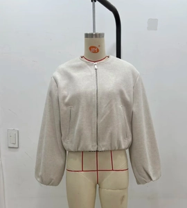 Détail d'une veste bomber beige zippée avec col rond et poignets côtelés sur mannequin
