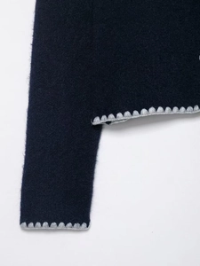 Detail of navy knit sweater showing grey crochet lace trim and fuzzy wool texture