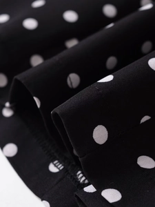 Close-up of black fabric with white polka dots showing stitching and texture details