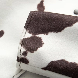 Detail of wool jacket cuff showing cow print pattern, zigzag stitching and a dark button