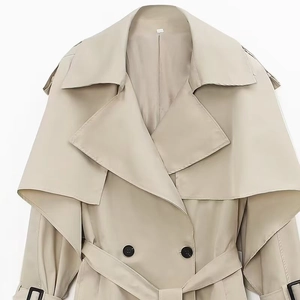 Detail of beige trench coat featuring large lapels and layered storm flap design