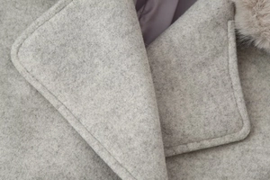 Macro detail of wool coat lapel with premium stitching and faux fur collar accessory