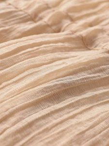 Macro detail of beige pleated fabric texture with elegant sheer ruffled effect