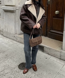 Street style view of a brown faux shearling jacket paired with a suede baguette handbag