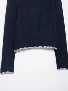Detail of dark blue knit cardigan showing soft texture and light gray scalloped trim