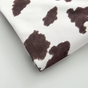 Detail of cow print jacket fabric featuring soft faux suede texture and neat brown patterns