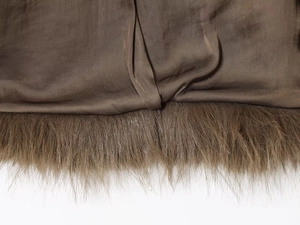Détail du manteau en fausse fourrure marron montrant les coutures et la texture