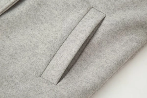 Detailed close-up of light gray wool blend jacket showing refined welt pocket and fabric texture