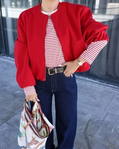 Detail view of a bright red bomber jacket with a round neck and ribbed hem finishing