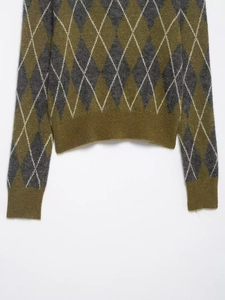 Close-up of olive green and dark grey argyle knit pattern with ribbed hem detail