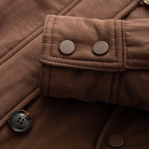 Close-up of brown denim jacket cuffs with metal snap buttons and high-quality stitching