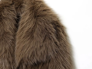 Gros plan sur la texture pelucheuse et le faux fourrure marron doux du col du manteau