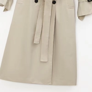 Detail of classic khaki trench coat featuring double-breasted buttons and matching waist belt